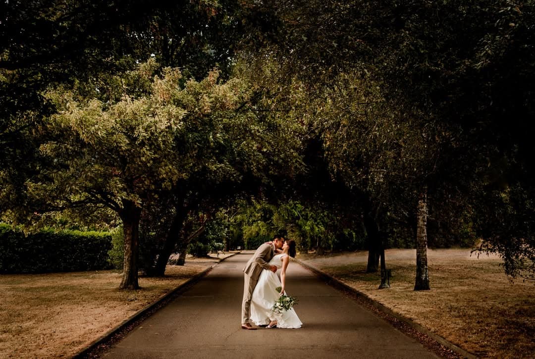 A couple on the tree-lined avenue through the estate grounds at golden hour