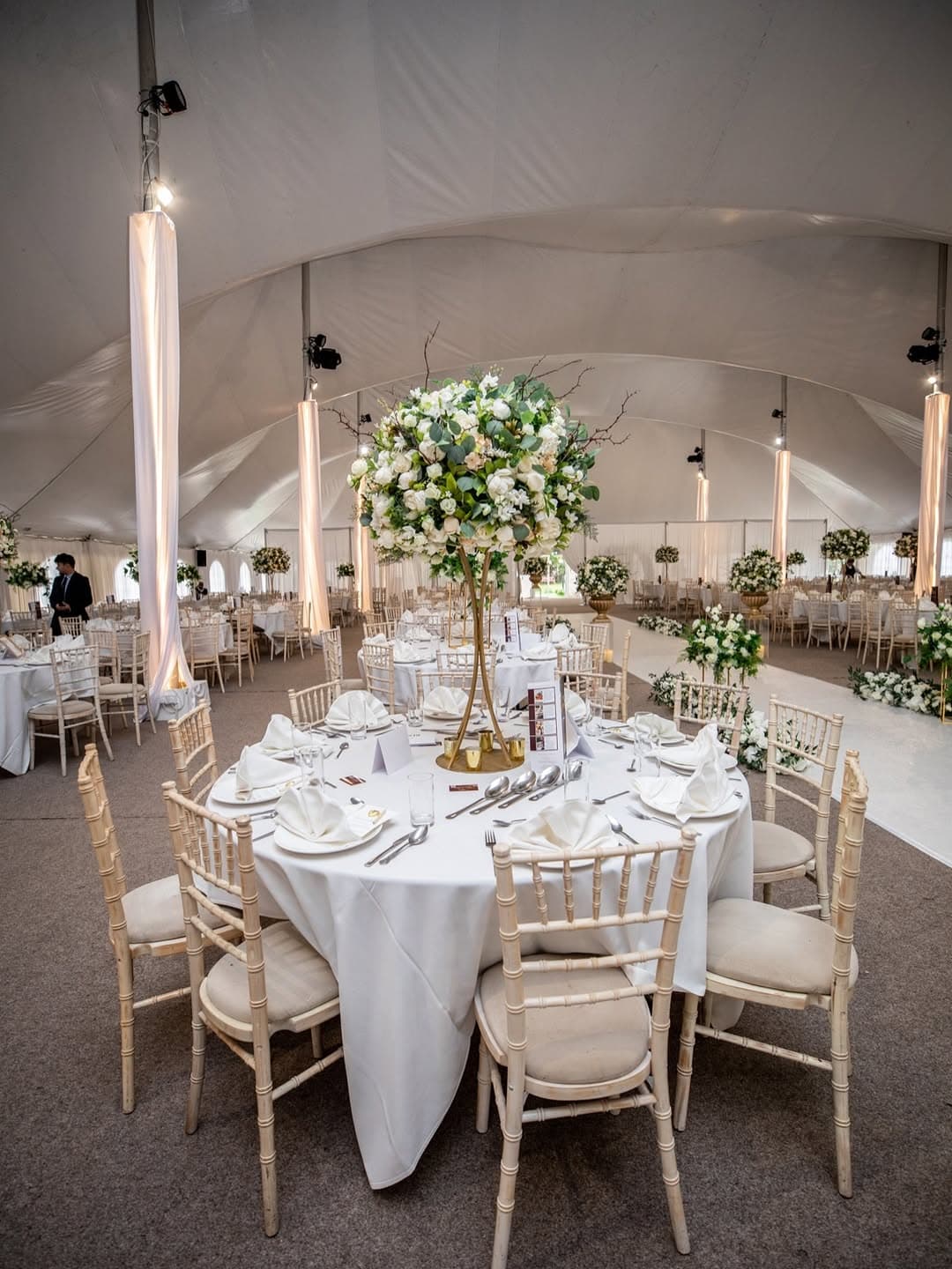 A tall floral centerpiece on a dressed wedding table