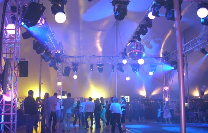 A corporate event with full lighting and a dancefloor under the marquee